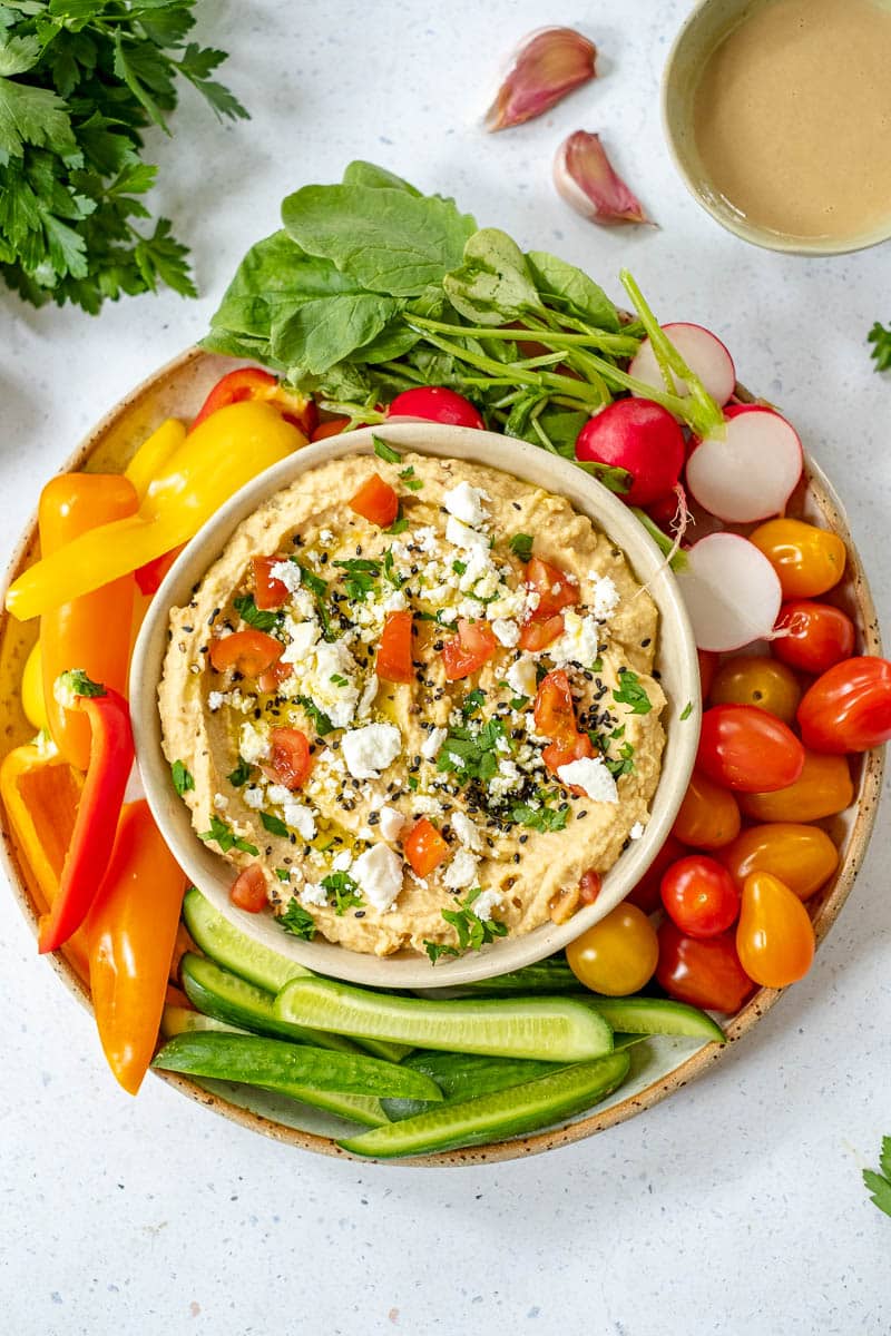 loaded hummus geserveerd met verse groentjes en ingrediënten errond